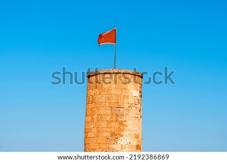The flag flutters in the wind over the ancient tower of the fortress