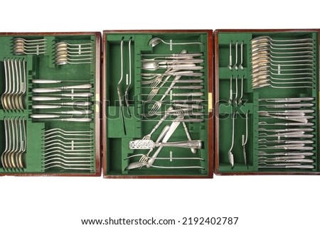 A large antique canteen of silver cutlery, including a variety of spoons, knives, forks and serving implements, all encased in a wooden set of drawers lined in green velvet felt. Royalty-Free Stock Photo #2192402787