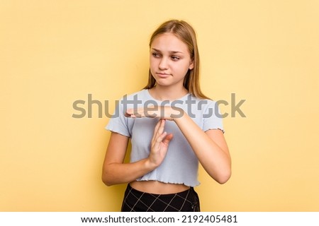 Young caucasian girl isolated on yellow background showing a timeout gesture.