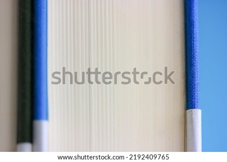 Macro photo of paper book in blue hardcover with white pages. Extremely close up shot of a book on a bookshelf. Concept of publishing literature, reading, culture. Back to school, college concept.