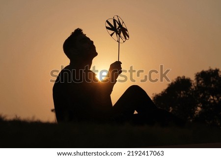 Happy young boy with a toy petal on a sunset background over a wheat field