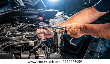 Auto mechanic working on car engine in mechanics garage. Repair service. authentic close-up shot - selective focus with motion blur Royalty-Free Stock Photo #2192423059