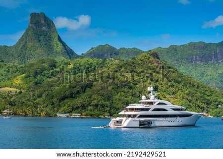 Large sixty meter Motor Yacht, Superyacht at anchor in Cook's Bay in tropical island of Moorea, French Polynesia. With verdant green landscape and big volcanic mountains in the background Royalty-Free Stock Photo #2192429521