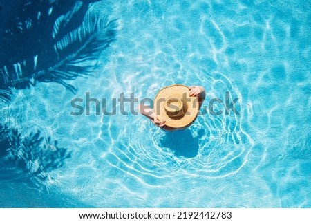 Top view of beautiful woman earing sunhat relaxing in swimming pool Royalty-Free Stock Photo #2192442783