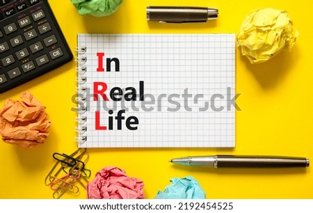 IRL in real life symbol. Concept words IRL in real life on white paper on white note on a beautiful yellow background. Black calculator and pen. Business and IRL in real life concept. Copy space.