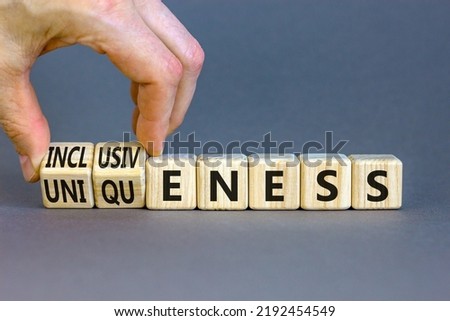 Inclusiveness and uniqueness symbol. Businessman turns wooden cubes, changes words inclusiveness to uniqueness. Beautiful grey background. Business, inclusiveness and uniqueness concept. Copy space.