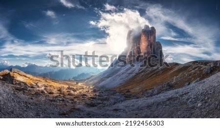 Mountain pass and blue sky with clouds at sunset in autumn. Beautiful panoramic landscape with rocks, alp mountains, stones, path, house, grass on hills. Tre Cime, Dolomites, Italy. Colorful scenery Royalty-Free Stock Photo #2192456303