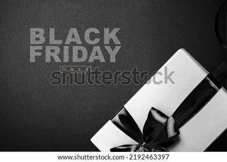 Gift box with black ribbon and Black Friday sale text on a black background. Black Friday concept