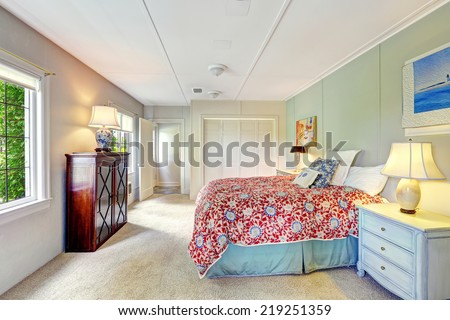 Bright simple bedroom interior with colorful bedding, old nightstand and wooden cabinet