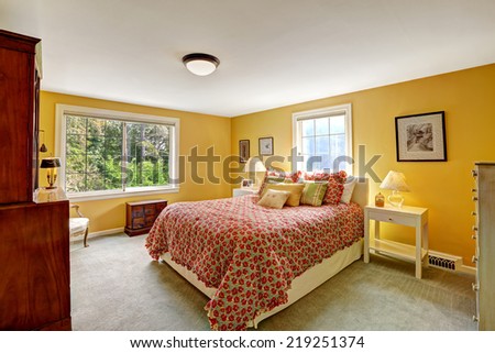 Cheerful bedroom interior in bright yellow color and red bedding