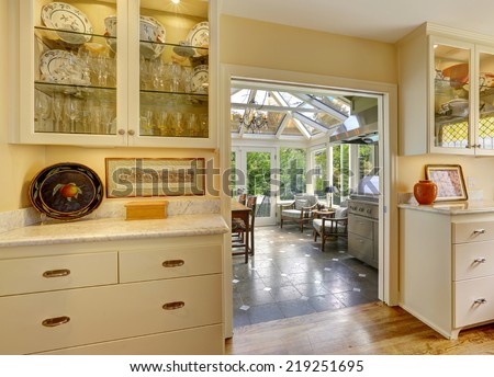 Kitchen room with exit to patio area in sun-room. Kitchen cabinets with glass doors and white granite tops