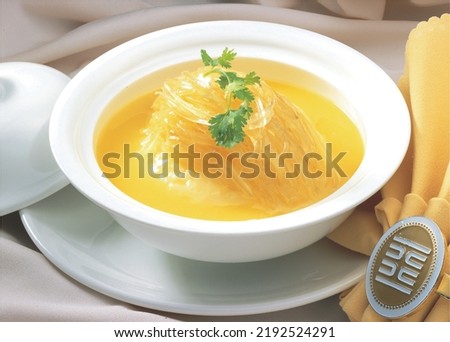 Chinese Shark's Fin Soup with brown sauce serve in Royal yellow bowl, decoration with bean sprouts and Coriander, on grey wooden background.