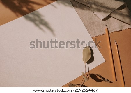 Aesthetic background with a4 paper mockup, pens, decorative eucalyptus twig, linen napkin. Branding, portfolio, web design template. Workplace of an artist.