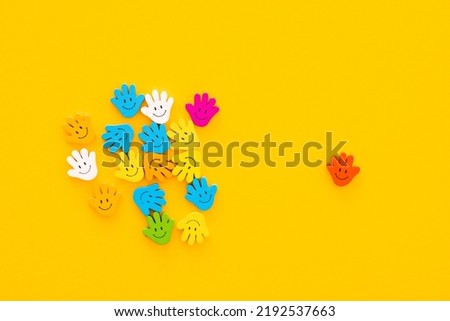 Colored wooden figures in the form hand with smiles on a yellow background