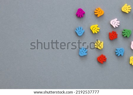 Colored wooden figures in the form hand with smiles on a grey background
