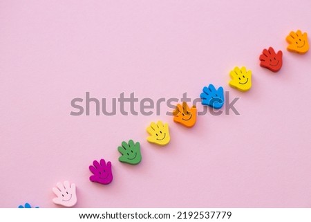 Colored wooden figures in the form hand with smiles on a pink background