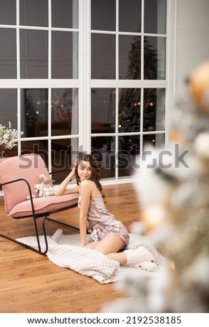 young beautiful girl in pajamas sits in the New Year's interior