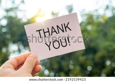 Thank you words written on white paper card, gratitude message with green garden background