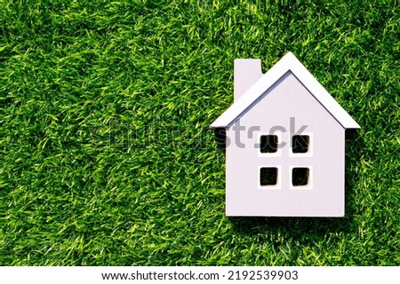 Inflation, property or mortgage concept. Little house over green grass. Copy space for text