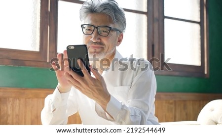 Fashionable elderly Asian man using a smart phone in the room. Royalty-Free Stock Photo #2192544649