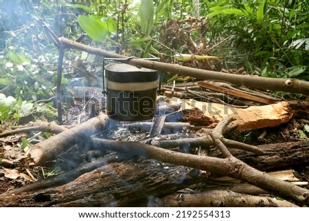 Rice cooking with military pot on bonfire. Camping in deep forest. (The pictures has noise and soft focus)