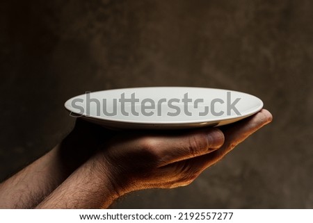 Male hands holding empty plate on dark background, lack of food, hunger and crisis concept
 Royalty-Free Stock Photo #2192557277