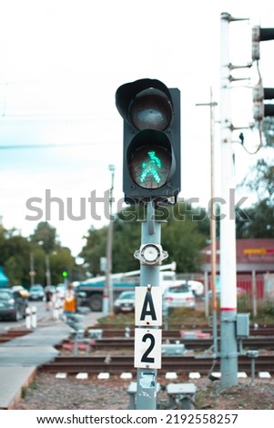 Traffic light with green man allowing railroad crossing, safe pedestrian crossing over railroad tracks