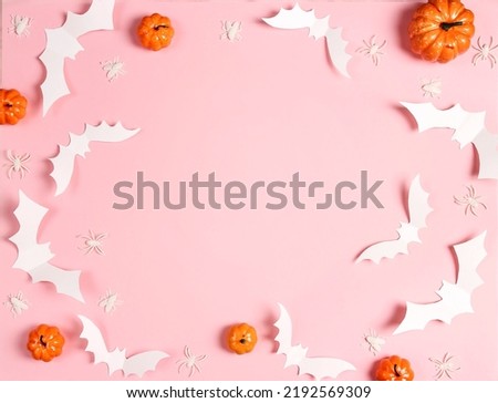 Halloween pink background with white bats, spiders and pumpkins. Flat lay, top view frame with copy space.