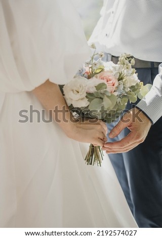 hands with wedding rings. hands of the bride and groom with wedding rings and bridal bouquet. the groom gently holds the bride's hand  Royalty-Free Stock Photo #2192574027