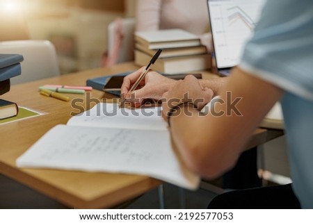 Close up of student sits in library, prepare for exam and making notes in notebook Royalty-Free Stock Photo #2192577053