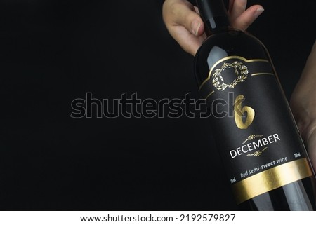 December 6th. Day 6 of month, Calendar date. Hands hold bottle of red wine with a calendar date on label.  Winter month, day of the year concept