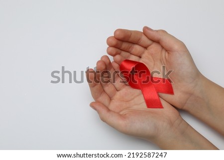 Little girl holding red ribbon on white background, closeup. AIDS disease awareness