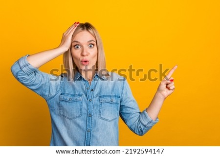 Photo of charming amazed young woman smiling pointing finger empty space isolated yellow color background.