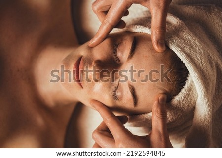 Top view photo of cosmetologist making facial massage treatment for patient woman face at spa salon. Beauty treatment. Facial beauty. Beauty skin.