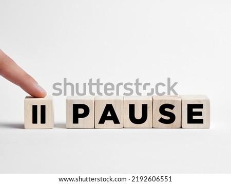 Finger presses the pause button on wooden cubes. Royalty-Free Stock Photo #2192606551