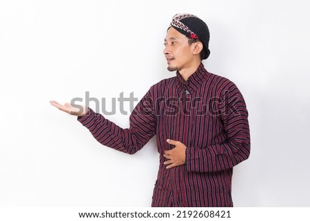 asian man with javanese traditional cloth lurik pointing with fingers to different directions isolated on white background
