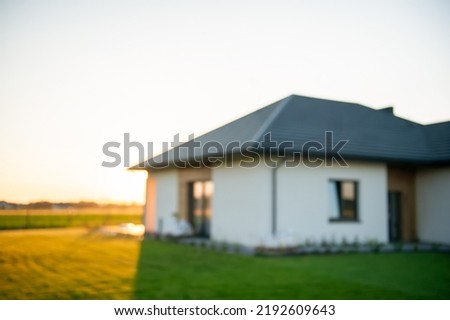 Blurred view of beautiful house with green lawn on sunny day