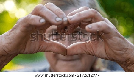 grandmother makes a heart with her hands. Selective focus. People.