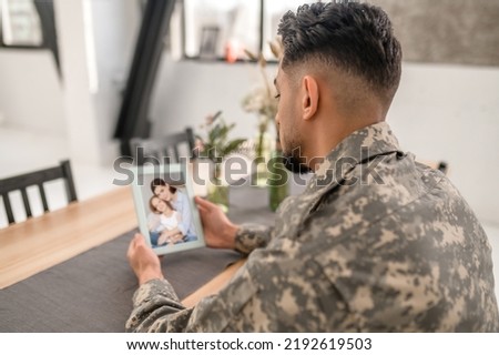 Army soldier looking at the framed family picture