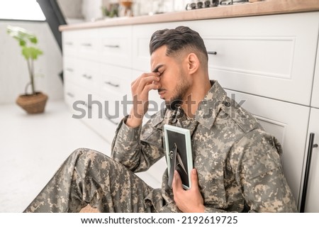 Sad army soldier holding the framed photograph in the hand