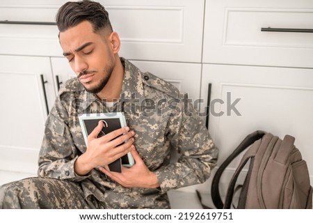 Sorrowful military man holding the picture in his hands