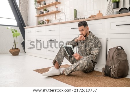 Despondent young soldier gazing at the picture in his hand