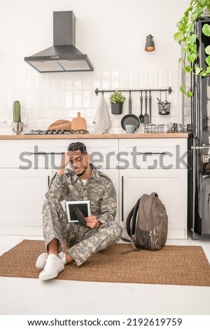 Cheerless young soldier looking at the photograph in his hand