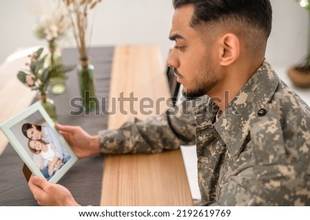 Serviceman looking at the framed photo at the kitchen table