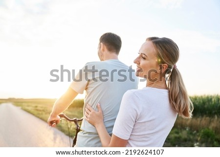 Rear view of caucasian couple having fun on one bike on village road 