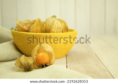 Small yellow physalis berries on a wooden background. Physalis fruits on a wooden table. Sweet yellow physalis berries. Copy space
