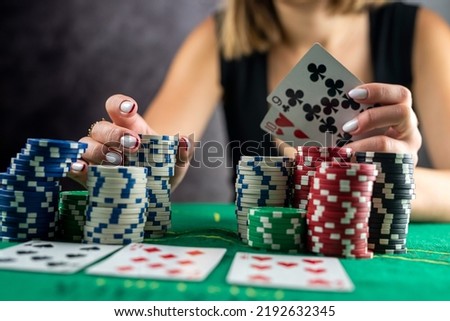 Female hand taking poker chips from pile at round poker table. risky bets in poker Royalty-Free Stock Photo #2192632345
