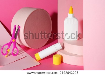 Composition with glue, paper and scissors on pink background