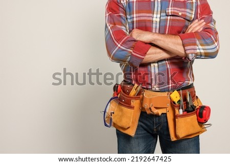 Professional builder with tool belt on light background, closeup. Space for text Royalty-Free Stock Photo #2192647425