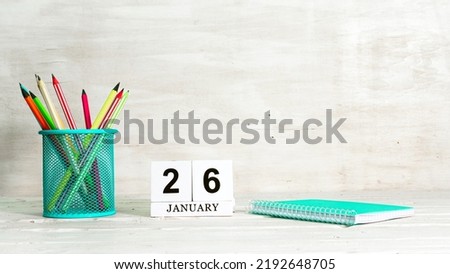 January 26 calendar. The concept of the date of the season. Pencils in a basket against the background of a notebook and the date of the month. Copy space calendar cube